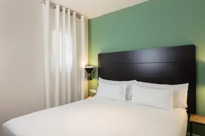 a bedroom with a white bed with a black headboard at Praktik Garden in Barcelona