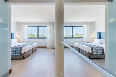 two beds in a room with two windows at Exe Campus in Bellaterra