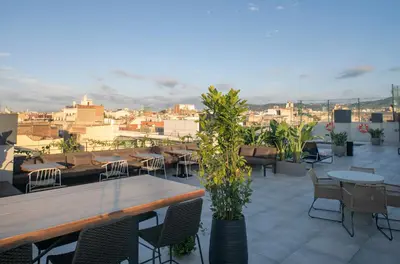 a rooftop patio with tables and chairs and a city at Silken Ramblas in Barcelona