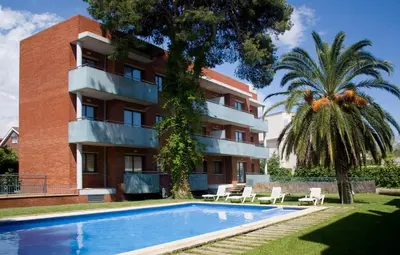 an apartment building with a swimming pool in front of a building at SG Costa BCN Apartments in Castelldefels