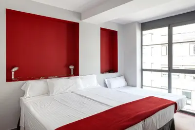 a bedroom with a white bed with a red wall at Ciutat Vella in Barcelona