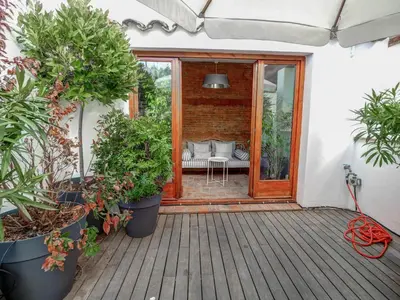 a patio with potted plants on a wooden deck at Beach Villa Aralinn by Hello Homes Sitges in Sitges