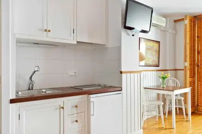 a kitchen with white cabinets and a sink and a table at Central - a 10 minutos de la paya in Sitges