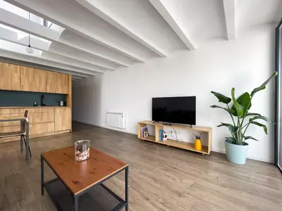 a living room with a table and a flat screen tv at loft en el centro in Vilanova i la Geltrú