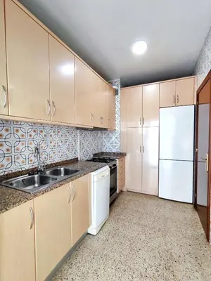 a kitchen with wooden cabinets and a sink and a refrigerator at Apartamento Diagonal Mar, cerca del Forum y Playa in Barcelona