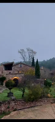 a stone building with an archway in a yard at Masia Vilatersana in Sant Llorenc Savall