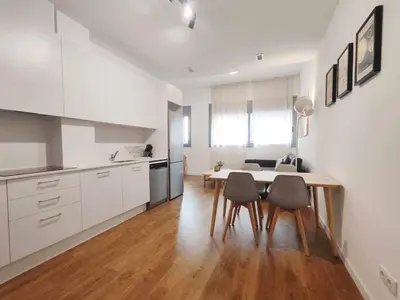 a kitchen with white cabinets and a table and chairs at Mazi Apartments Loft in Mataró