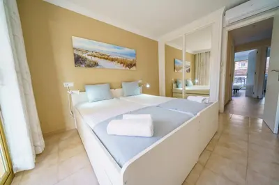 a large white bed in a room with a mirror at HomeHolidaysRentals Liberty - Costa Barcelona in Pineda de Mar