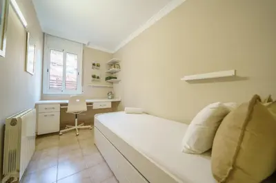 a white bedroom with a bed and a desk at HomeHolidaysRentals Liberty - Costa Barcelona in Pineda de Mar