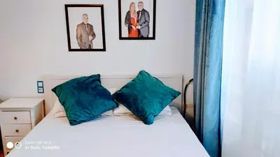 a bed with two blue pillows and two pictures on the wall at Hostal Estudios in Badalona