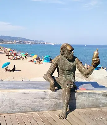 a statue of a man sitting on a wall at the beach at Hostal Estudios in Badalona