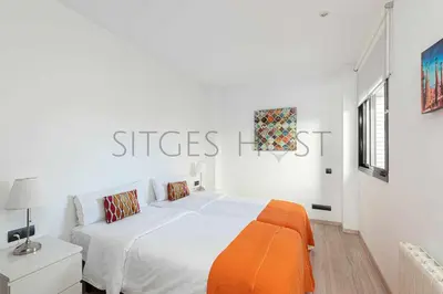 a white bedroom with a large bed with an orange blanket at Sitges PORT - Con piscina, a 5 minutos de la playa in Sitges