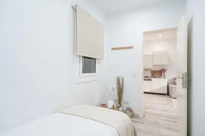 a white bedroom with a bed and a kitchen at Apartment Next to Sagrada Familia, the Essence of Barcelona in Barcelona
