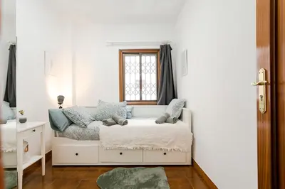 a white bedroom with a bed and a window at Barcelona Beach Home in Barcelona