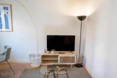 a living room with a table and a tv at Feelathome Stadium Apartments in Hospitalet de Llobregat