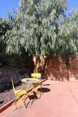 a yellow picnic table and a bench under a tree at El Cedre Blau Vivienda con piscina en Granollers in Granollers