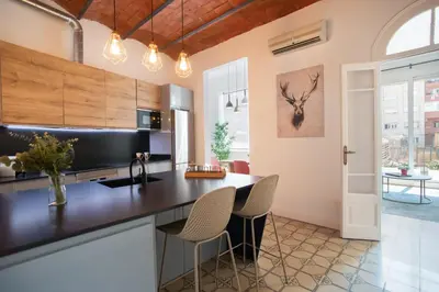 a kitchen with a black counter top and chairs at Tendency Apartments Miro 8 in Barcelona