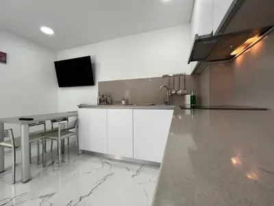 a kitchen with a counter and a sink and a table at Apartamentos Rosa de Abril in Teià