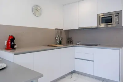 a kitchen with white cabinets and a clock on the wall at Apartamentos Rosa de Abril in Teià