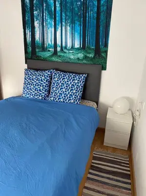 a bedroom with a blue bed with a painting on the wall at Pisito bonito y funcional en Pineda De Mar in Pineda de Mar