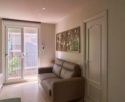 a living room with a couch and a sliding glass door at Stay U-nique Apartments Torre Damians in Barcelona