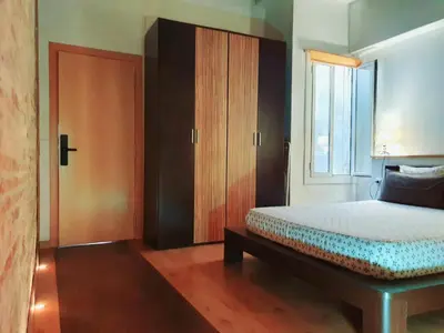 a bedroom with a bed with a wooden door and a window at Apartamento Llibertat centro in Vilanova i la Geltrú