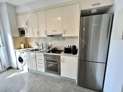 a kitchen with white cabinets and a stainless steel refrigerator at Loft moderno en buena ubicación in Terrassa