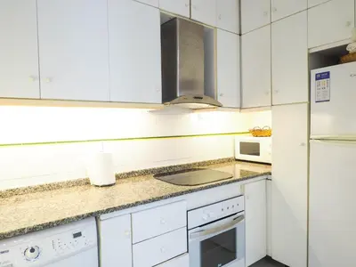 a white kitchen with a sink and a refrigerator at Sunflower Apartment by Hello Homes Sitges in Sitges