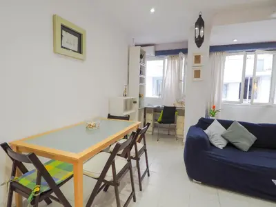 a living room with a table and a blue couch at Sunflower Apartment by Hello Homes Sitges in Sitges