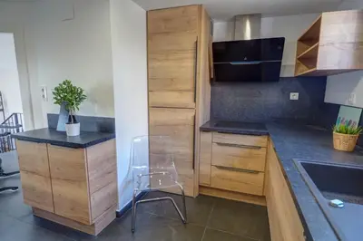 a kitchen with wooden cabinets and a chair in it at The Moonlight Sea View by Hello Homes Sitges in Sitges