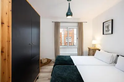 a bedroom with two beds and a black cabinet at Vintage 3 Bdr Apartment in Esplugues de Llobregat