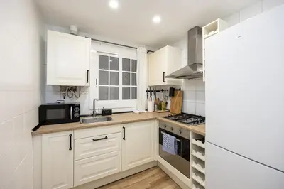 a kitchen with white cabinets and a sink and a microwave at Vintage 3 Bdr Apartment in Esplugues de Llobregat