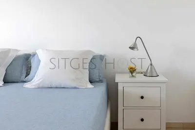 a bedroom with a bed and a nightstand with a lamp at Sitges ARENA - dos piscinas frente al mar in Sitges