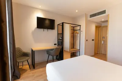 a bedroom with a bed and a desk and a tv at Petit Palace Eixample in Barcelona