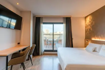 a hotel room with a large bed and a balcony at Petit Palace Eixample in Barcelona