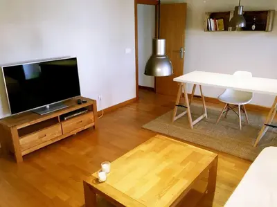 a living room with a flat screen tv and a table at MODERNO APARTAMENTO EN EL CENTRO in Vilanova i la Geltrú