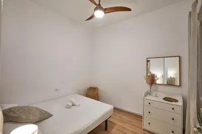 a white bedroom with a ceiling fan and a dresser at BBarcelona Calabria Flat in Barcelona