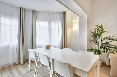 a white dining room with a white table and chairs at BBarcelona Calabria Flat in Barcelona