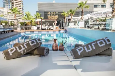 a pool at a hotel with palm trees and buildings at Hilton Diagonal Mar Barcelona in Barcelona