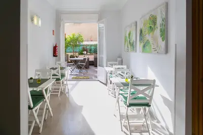 a restaurant with white tables and green chairs at Blanc Guest House in Barcelona