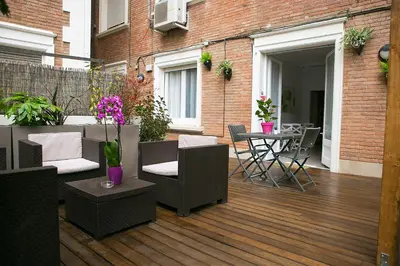 an outdoor deck with chairs and a table with flowers at Blanc Guest House in Barcelona