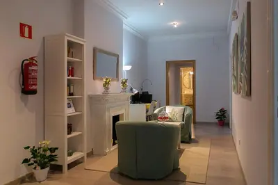a living room with a fireplace and a green chair at Blanc Guest House in Barcelona