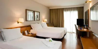 a hotel room with two beds and a television at Ciudad de Castelldefels in Castelldefels