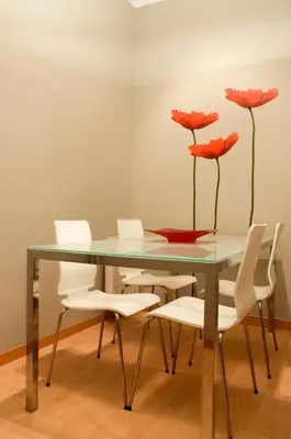 a dining room table with white chairs and red flowers at Barcelonaguest in Barcelona