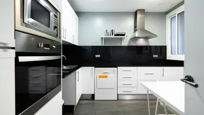 a kitchen with white cabinets and a black and white appliance at Magnificent 4 bedroom apartment in Eixample in Barcelona