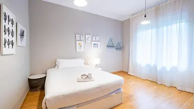 a white bedroom with a bed and a window at Magnificent 4 bedroom apartment in Eixample in Barcelona