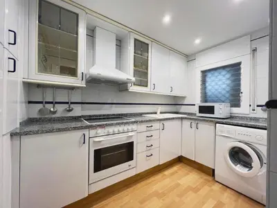 a kitchen with white cabinets and a washer and dryer at Hauzify I Apartament Can Reig in San Pol de Mar