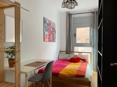 a bedroom with a desk and a bed with a colorful blanket at Oasis familiar Terrassa in Terrassa