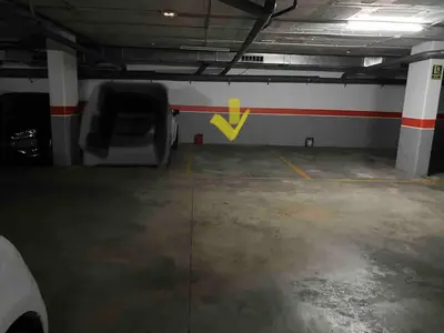 an empty parking garage with a yellow arrow on the wall at Oasis familiar Terrassa in Terrassa