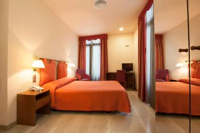 a hotel room with two beds and a mirror at Alba Hotel in Barcelona